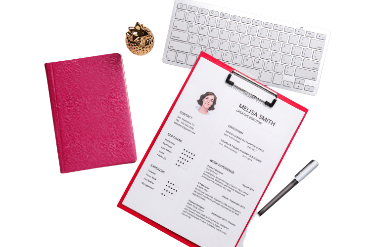 a keyboard , a purse and a resume on clipboard with a pen
